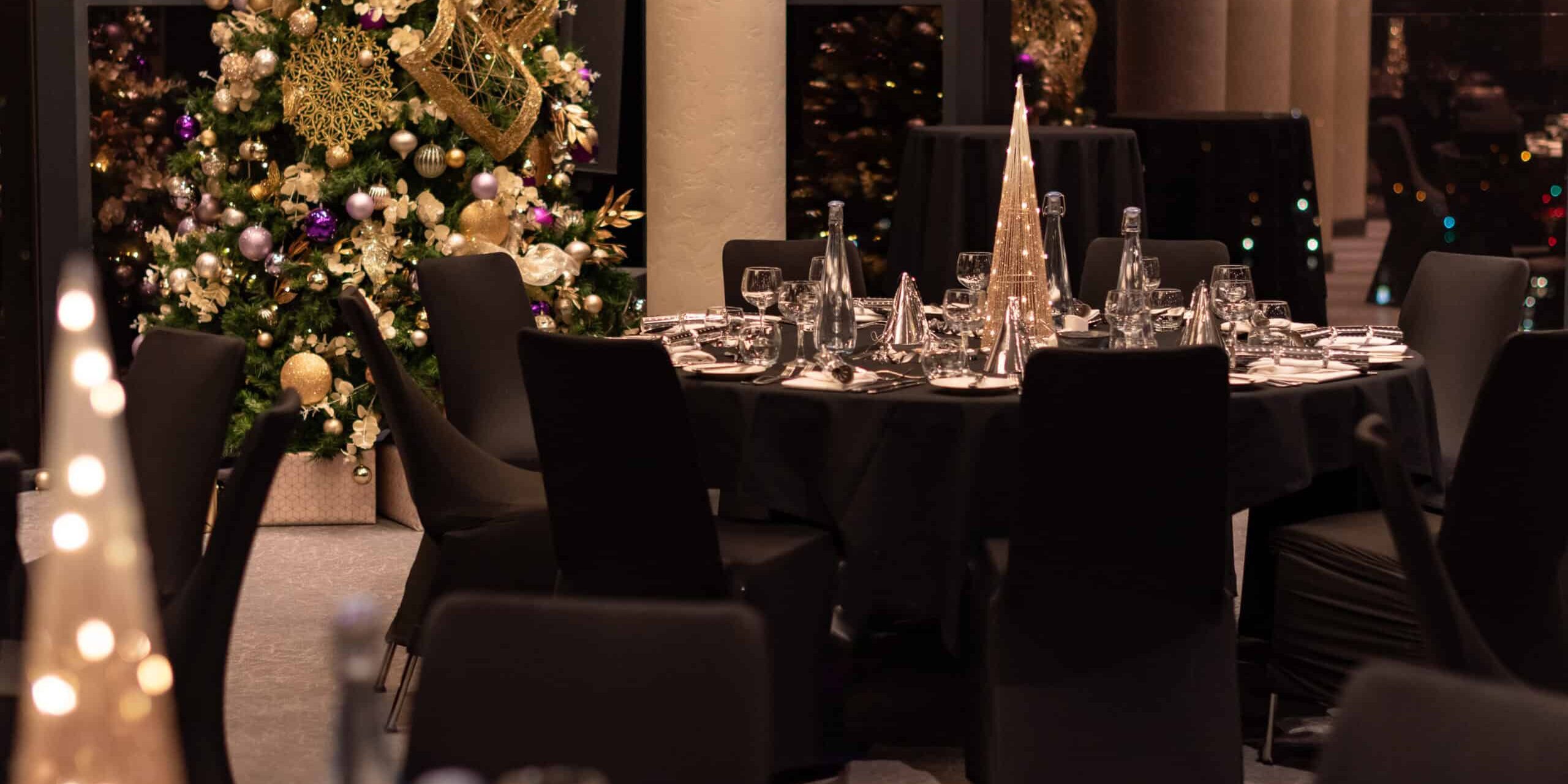 Round tables laid for Christmas dinner with a Christmas tree in the background